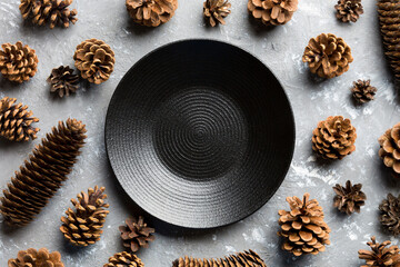 Top view of festive plate with pine cones on cement background. New Year dinner concept