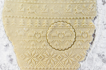 Dough rolled out on the table with a New Year's pattern. Making cookies on the New Year's table, a festive treat.