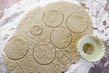 Dough rolled out on the table with a New Year's pattern. Making cookies on the New Year's table, a festive treat.