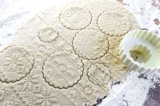 Dough rolled out on the table with a New Year's pattern. Making cookies on the New Year's table, a festive treat.