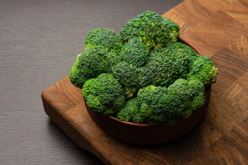 Fresh green broccoli on a wooden butt cutting board. Dark graphite background.