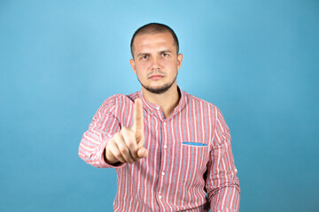 Russian business man over blue background showing and pointing up with fingers number one while is serious