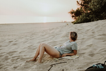 Fototapeta na wymiar girl on the beach sitting on the sand evening