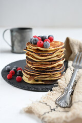 Plate with pancakes and berries on white table