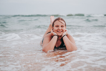 teen girl in a swimsuit on the beach. overweight, smiling.
