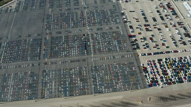 Aerial video of stock car parking. Flying over big industrial zone with big parking lot of brand new cars. Many cars waiting for sale and transportation. Automobile industry.
