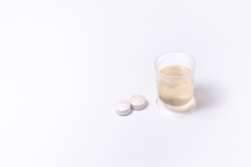measuring cup with medicine and pills on white background
