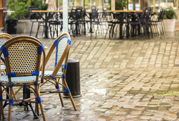 Fototapeta na wymiar Empty terrace of the restaurant after the rain, wet wooden chairs and tables on the street of Barcelona, Spain