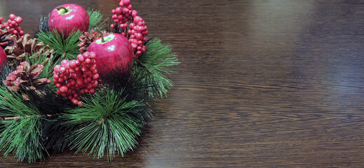 New year banner with a festive wreath on a wooden table. Christmas wreath with red berries and pine...