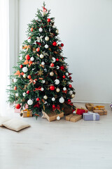 Christmas tree with gifts of garland lights for the new year in the interior of the white room as a backdrop