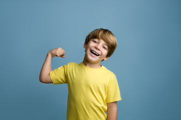 Portrait of cute kid boy showing the muscles of his arms. © BYPOLO