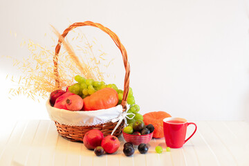 Orange pumpkins, berries of grapes and ginger, a red mug with juice on a white background, arranged along the contour, place for text,view from above.Frame of autumn fruits, vegetables and berries