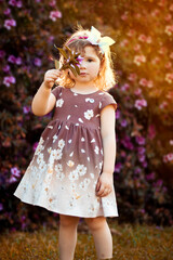 Fototapeta premium Menina loira, criança pequena, brincando em meio a um jardim de azaleias, marcando o início da primavera. Menina sorrindo, criança feliz