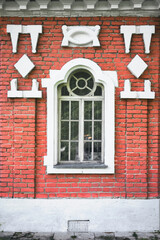 The window of an old brick building beautifully decorated with bas-reliefs. Exterior of old brick house.