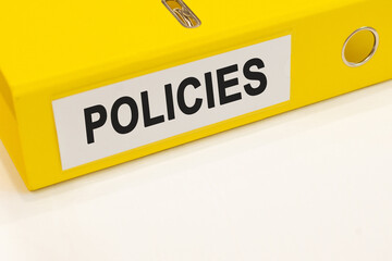The word policies on a white background with a yellow folder. Business concept
