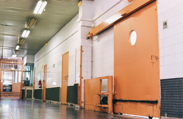 Old prison corridor or aisle with automatic sliding metal gates or doors. Controlled access in jail.