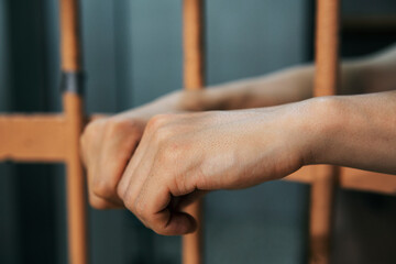 Prisoner waiting for the handcuffs. Before the escorting. Man's hands on the bars of the prison or...