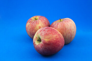 Three apples of the fuji type isolated on a blue background
