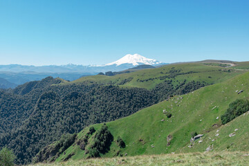 Fototapeta premium Scenic view of the highest peak in Europe, mount Elbrus with green hills on a Sunny summer day.