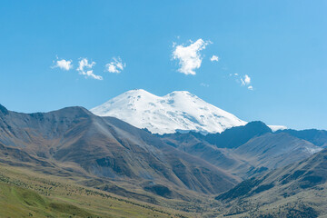 Fototapeta premium Scenic view of the highest peak in Europe, mount Elbrus with green hills on a Sunny summer day.