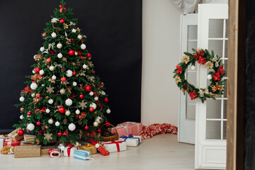 Christmas tree decorated with toys with gifts in the interior of the room black background new year