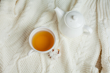 A mug of hot tea on a knitted blanket. Cozy autumn. Winter breakfast. Cotton.