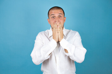 Russian business man wearing white shirt standing over blue background surprised with hand on head...