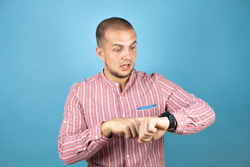 Russian business man over blue background surprised and pointing his watch because it's late