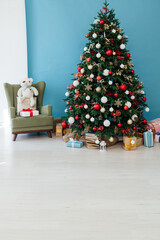Christmas tree pine decorated with toys with gifts in the interior of the room blue background New Year