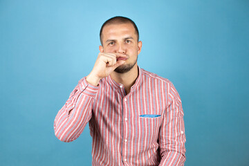 Russian business man over blue background mouth and lips shut as zip with fingers. Secret and...