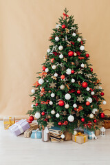 Christmas tree pine decorated with toys with gifts in the interior beige background new year