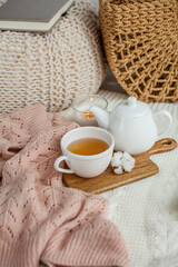 A mug of hot tea, a teapot, a wooden stand on an ottoman. Cozy autumn. Winter breakfast. Cotton.