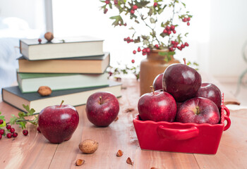 Red apples, walnuts and hawthorn berries. Autumn fruits and vegetables. Enjoy your time with books.