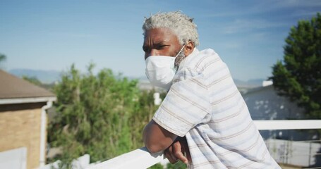 Senior man wearing face mask standing in the balcony - Powered by Adobe