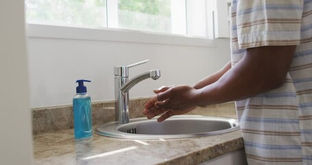 Mid section of man washing his hands in the sink - Powered by Adobe