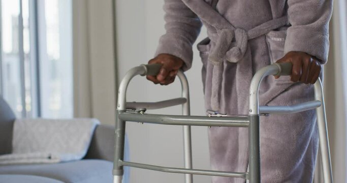 Mid section of senior man using zimmer frame to walk at home
