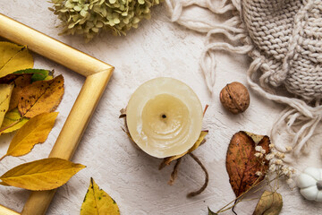 Fototapeta na wymiar Flat lay candle with fallen leaves, dry hydrangea, sweater. Autumn cozy concept