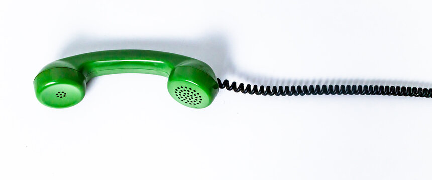 Old green phone headset with twisted cord, isolated on white background