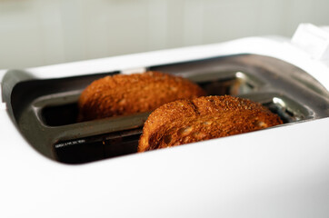 Two roasted toast bread popping up of toaster.