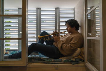 Young man playing trumpet at home