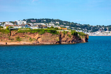 Obraz premium Permian red sandstone cliffs in the town of Torquay Devon England UK showing strata and a partially-walled cave.