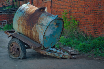 Old rusty tanker truck trailer on brick wall background.