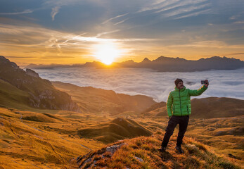 Amazing view on Dolomiti peaks at the summer sunrise. Tourist man takes a selfie in the mountains waiting for the sunset. Trentino Alto Adige, Dolomites Alps, South Tyrol, Italy. Odle mountain range.