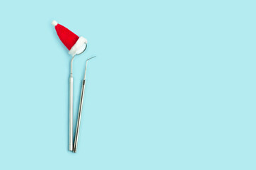 dental tools for new year, mirror and probe in santa hat on blue background. Creative medical christmas winter background. Health care, hygiene concept. Copy space, place for text