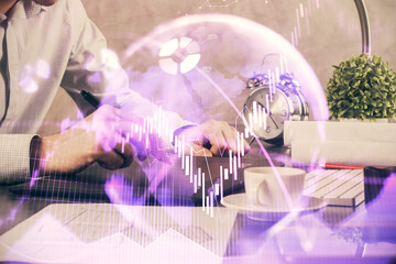 Double exposure of man's hands holding and using a phone and financial graph drawing. Analysis concept.