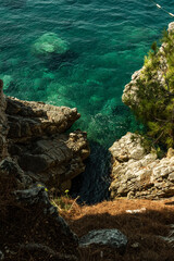 Rocky cliffs with pure clean green and blue water of Adriatic sea near Sveti Stefan island. Scary view from top.
