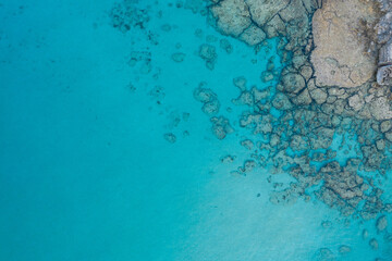 An aerial view of the beautiful Mediterranean Sea, where you can see the cracked rocky textured underwater corals and the clean turquoise water of Protaras, Cyprus,	