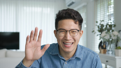 Portrait or headshot of young adult asian handsome man or model wearing eye glasses with cool hair big smiling confident and looking to camera with feeling happy and positive in living room at home.