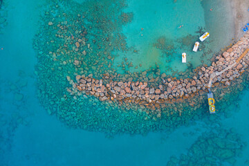 Aerial shot of boats on a crystal clear sea surrounded by rocks in Protaras, Cyprus	