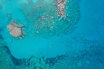 An aerial view of the beautiful Mediterranean Sea, where you can see the cracked rocky textured underwater corals and the clean turquoise water of Protaras, Cyprus,